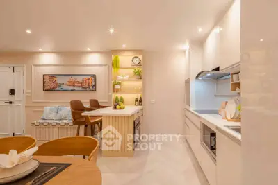 Modern kitchen with open layout and stylish dining area, featuring sleek cabinetry and elegant lighting.