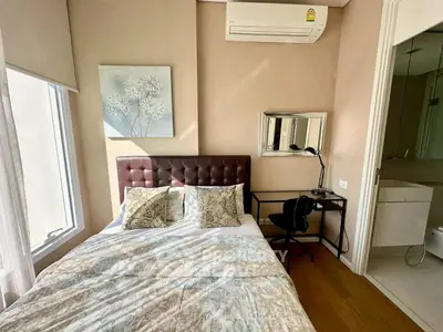 Cozy bedroom with modern decor and ensuite bathroom, featuring air conditioning and stylish furnishings.
