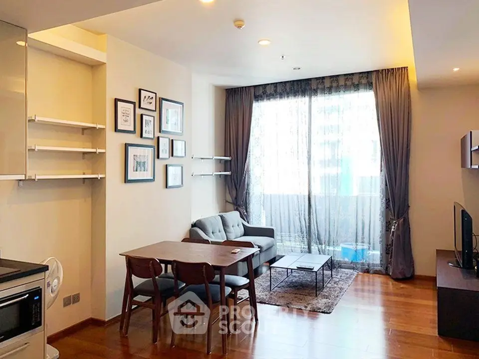 Modern living room with wooden flooring, cozy seating, and large window for natural light.