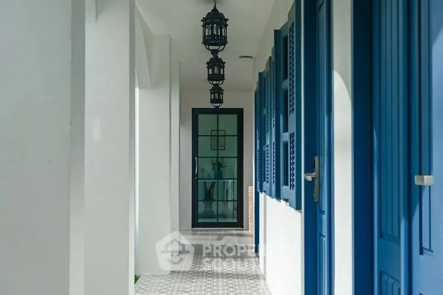 Charming corridor with blue doors and elegant hanging lanterns in a modern building.