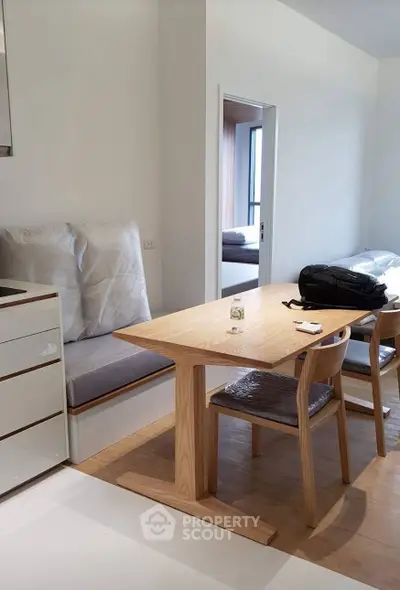 Modern dining area with wooden table and chairs in a cozy apartment setting.