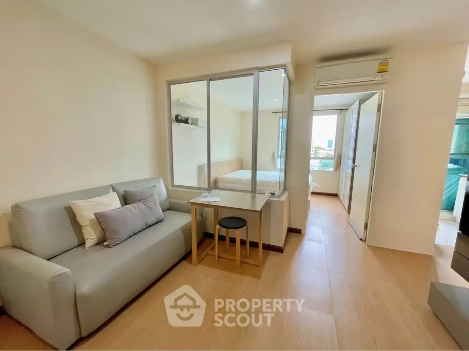 Modern apartment interior with cozy living room and bedroom view, featuring sleek furniture and natural light.