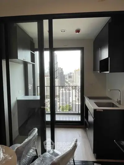 Modern kitchen with city view and sleek cabinetry in high-rise apartment.