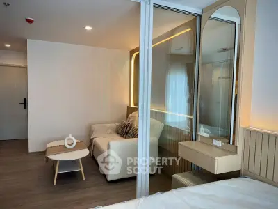 Modern studio apartment with stylish living area and cozy bedroom separated by glass partition.