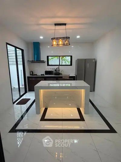 Modern kitchen with sleek island and stylish lighting, featuring a closed layout and contemporary appliances.