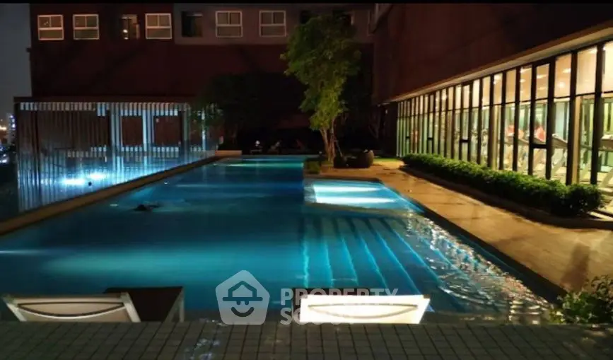 Luxurious rooftop pool with ambient lighting and city view, perfect for relaxation and leisure.