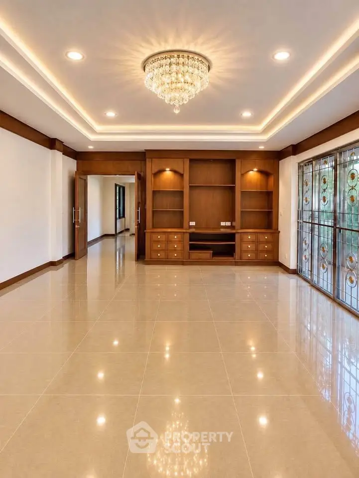 Spacious living room with elegant chandelier and built-in wooden shelves