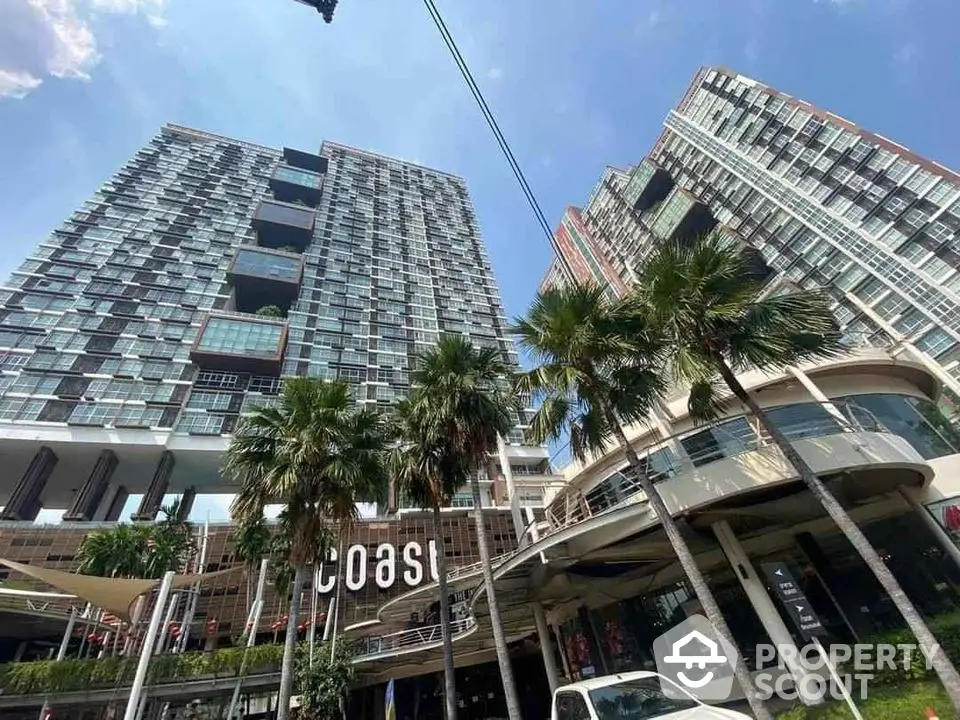 Modern high-rise condominium with palm trees and blue sky