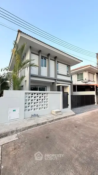 Modern two-story house with sleek design and spacious driveway in a suburban neighborhood.