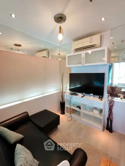 Modern living room with sleek black sofa and wall-mounted TV in stylish apartment.