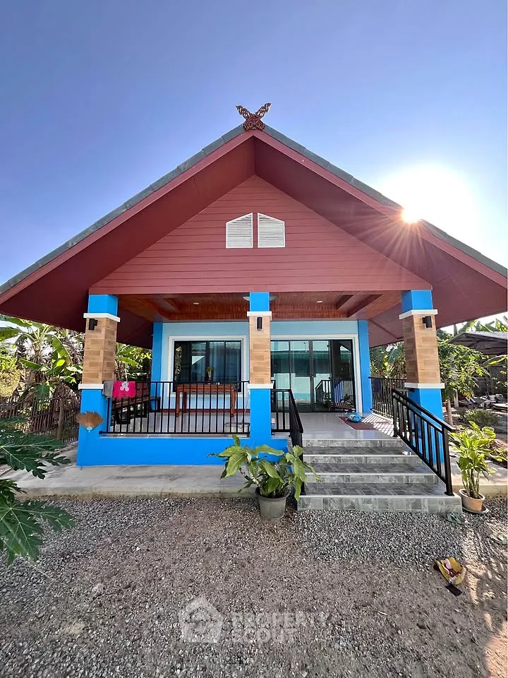 Charming single-story house with vibrant blue accents and inviting front porch.