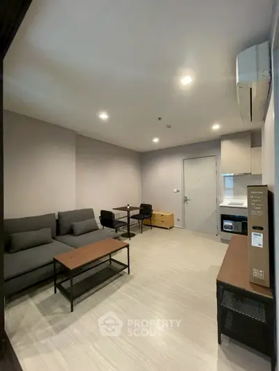 Modern living room with sleek furniture and open kitchen layout in a cozy apartment.