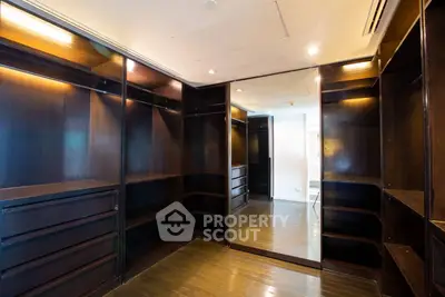 Spacious walk-in closet with dark wood shelving and mirrored door, perfect for luxury storage solutions.