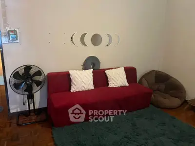 Cozy living room with red sofa, decorative wall art, and plush seating area.