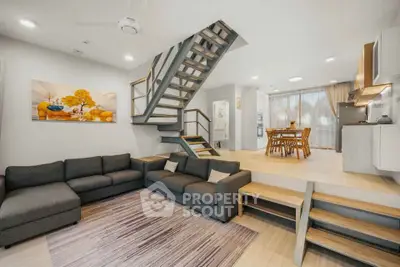 Modern open-plan living room with stylish staircase and cozy dining area.
