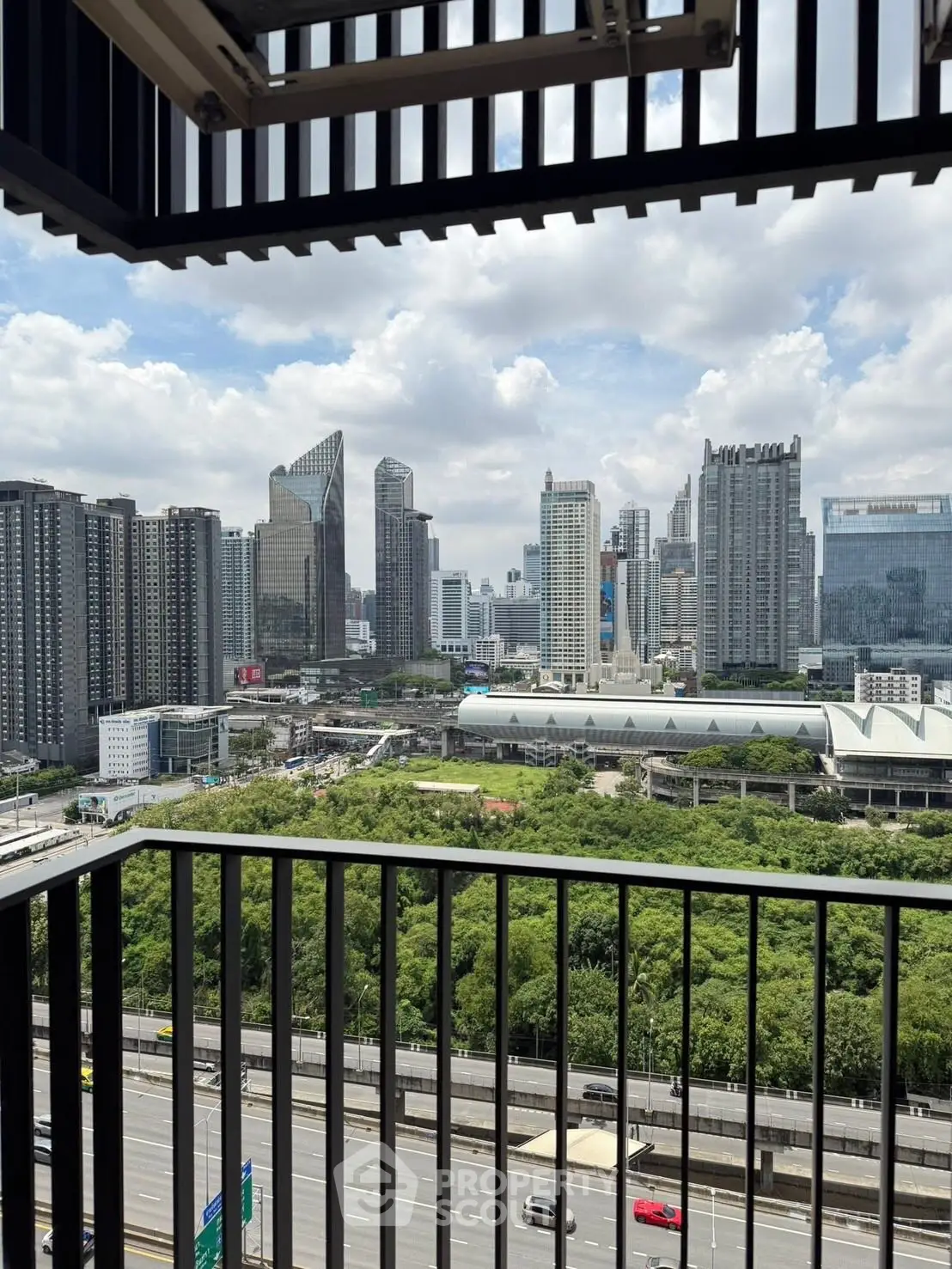 Stunning cityscape view from a high-rise balcony overlooking lush greenery and urban skyline.