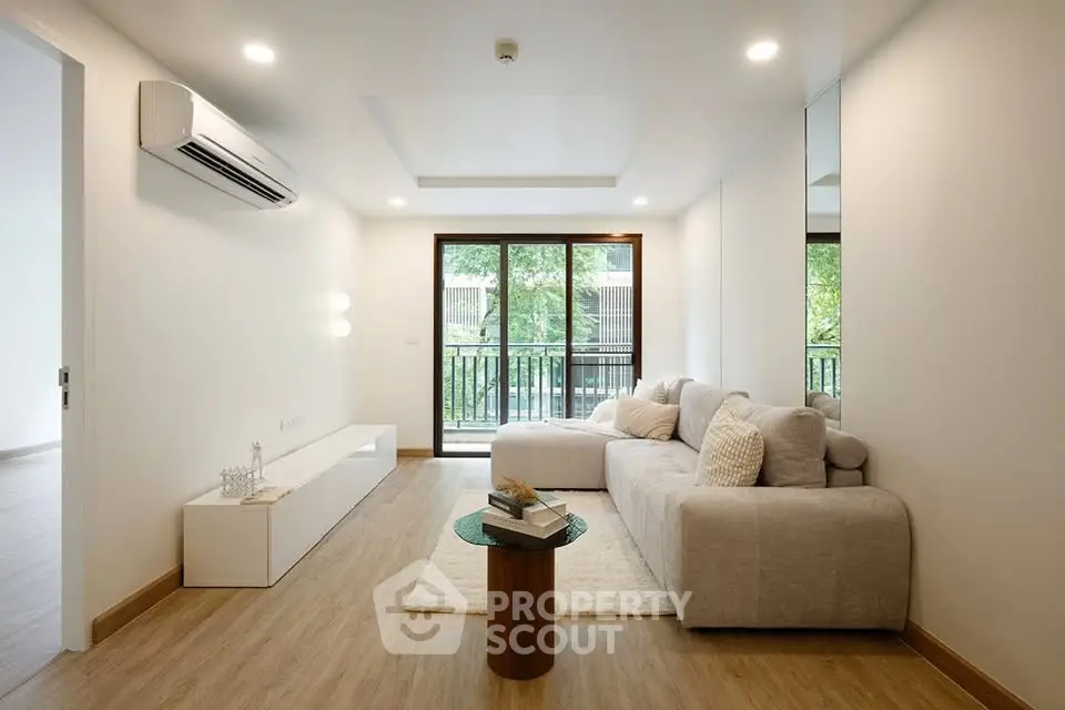 Modern living room with large windows and cozy sofa, featuring elegant wooden flooring.