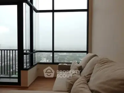 Spacious living room with large windows offering a stunning city view, perfect for relaxation and entertaining.