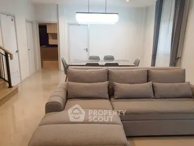 Spacious living room with modern gray sofa and dining area in open layout