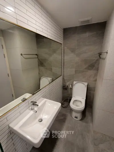 Modern bathroom with sleek sink and toilet, featuring elegant tile design.