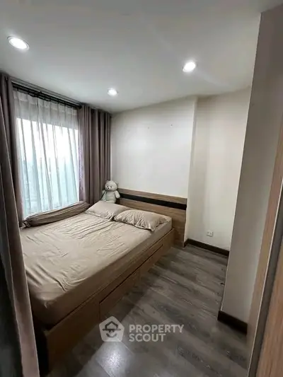 Cozy bedroom with large window and modern decor, perfect for relaxation.