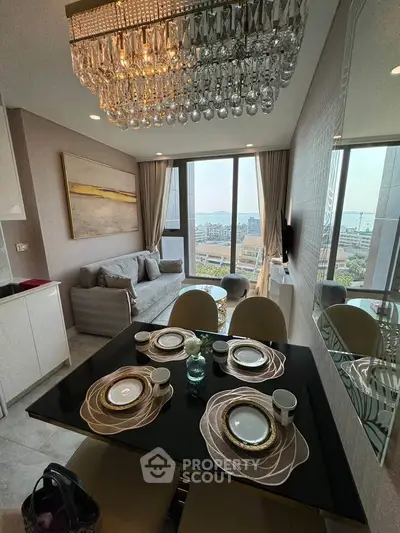 Luxurious dining and living area with elegant chandelier and stunning city view.