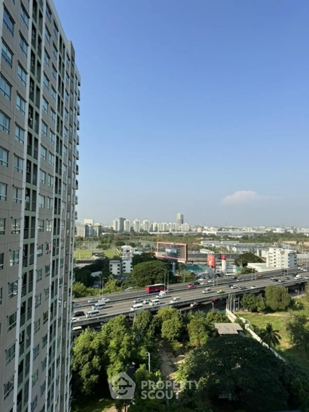 Stunning cityscape view from high-rise apartment balcony overlooking urban skyline and highway.