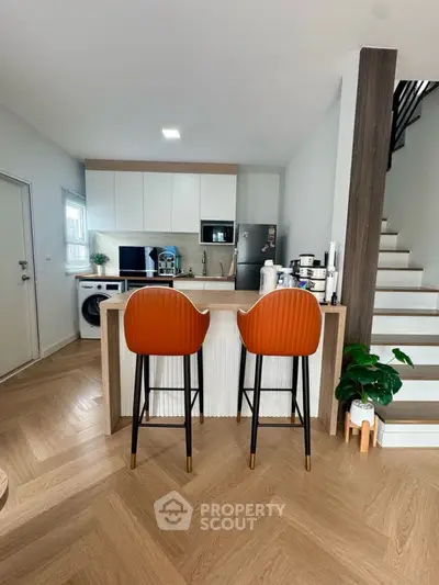 Modern kitchen with open layout, stylish bar stools, and sleek appliances in a cozy home setting.