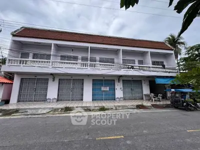 Spacious two-story commercial building with multiple garage doors and a tiled roof, ideal for business opportunities.