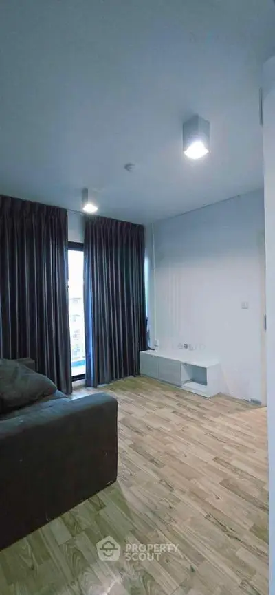 Spacious living room with wooden flooring and large windows for natural light.