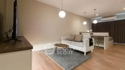 Modern living room with cozy sofa, wooden flooring, and stylish lighting in open layout apartment.