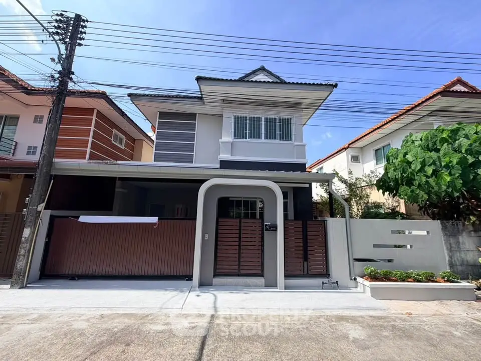 Charming two-story house with modern facade and gated entrance in a suburban neighborhood.