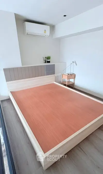 Modern minimalist bedroom with air conditioning and stylish wooden bed frame.