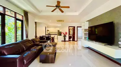 Spacious modern living room with leather sofa and large TV, open to dining and kitchen area.