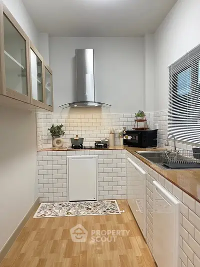 Modern kitchen with sleek design, featuring white subway tiles and wooden countertops.