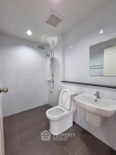 Modern bathroom with sleek fixtures and minimalist design, featuring a shower and toilet.