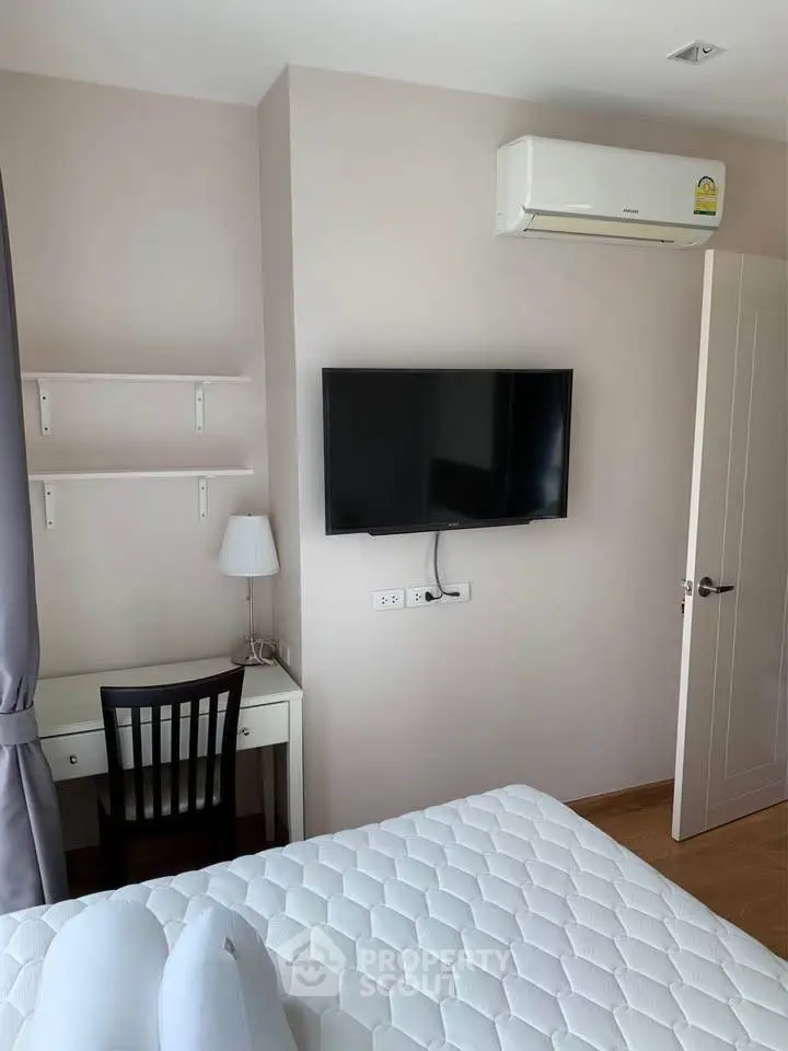 Cozy bedroom with wall-mounted TV and air conditioning, perfect for relaxation.