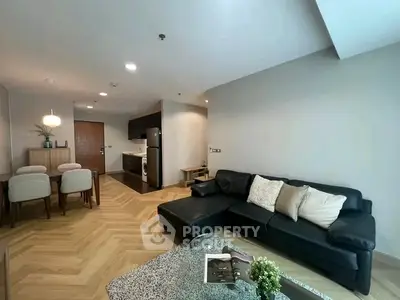 Modern living room with sleek black sofa and open kitchen layout in stylish apartment.