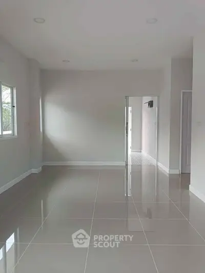 Spacious empty room with glossy tiled floor and natural light