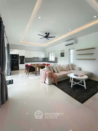 Spacious modern living room with open kitchen, sleek design, and elegant furnishings in a luxurious home.