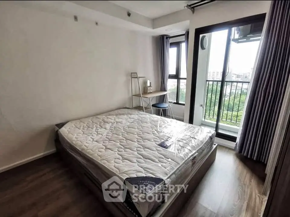 Modern bedroom with balcony view, featuring a new mattress and stylish desk setup.