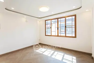 Bright and spacious empty room with large window and modern ceiling lights.