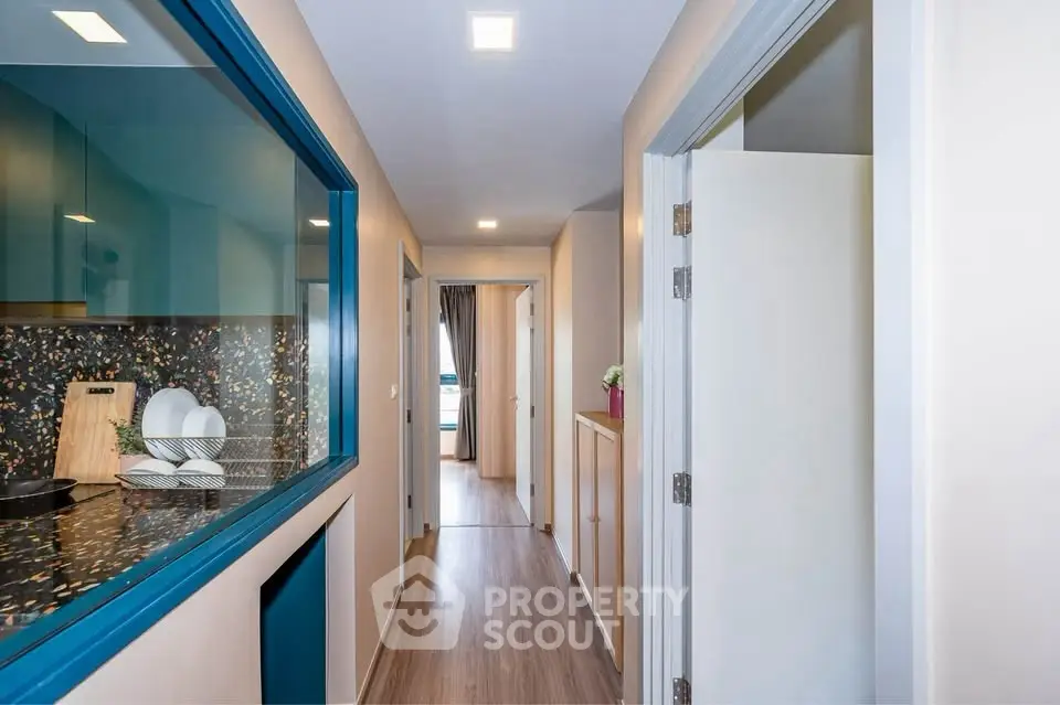 Modern apartment hallway with sleek kitchen and wooden flooring