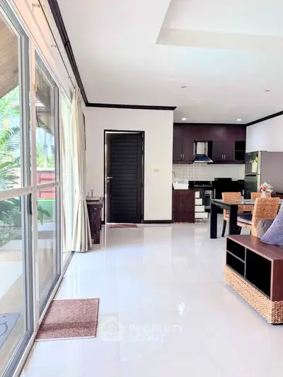 Spacious open-plan living room with modern kitchen and large windows for natural light.