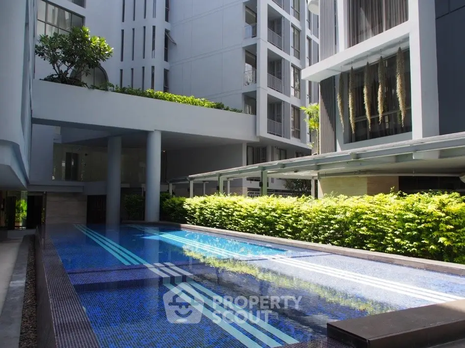 Luxurious modern apartment building with sleek pool and lush greenery