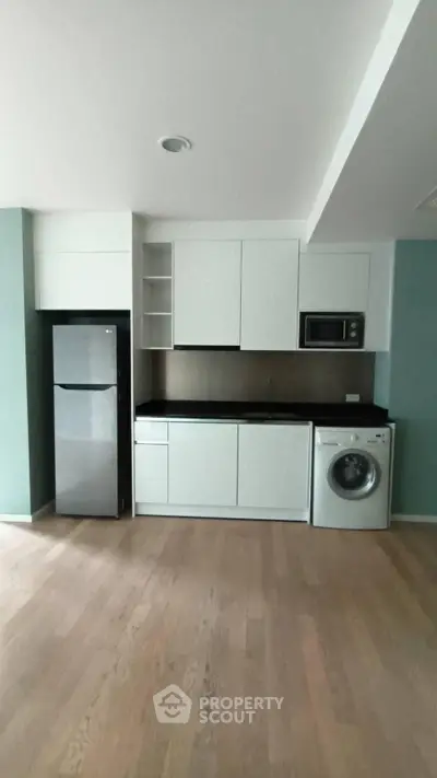 Modern kitchen with sleek appliances and wooden flooring in a stylish apartment.