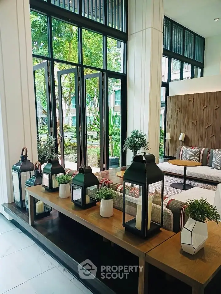 Elegant living room with large windows and stylish decor overlooking lush garden.