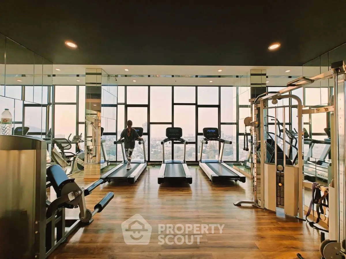 Luxurious high-rise gym with panoramic city views and modern fitness equipment.