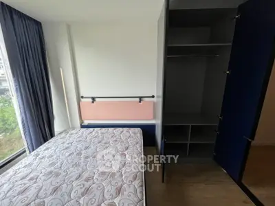 Modern bedroom with large window and built-in wardrobe, offering ample natural light and storage space.
