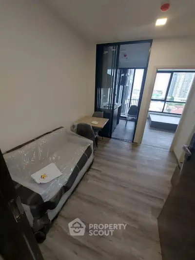 Modern apartment interior with cozy living area and large windows offering city views.